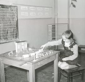 Dziewczynka przy papierowej makiecie linii kolejowej