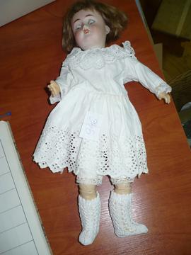 Lalka w białej ażurowej sukience zapinanej na plecach
